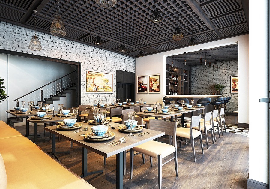 A modern restaurant interior with elegant table settings, wooden furniture, and a stylish bar area in the background, highlighted by a sophisticated ceiling design and brick walls.
