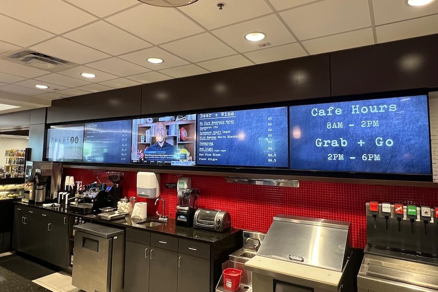 five wall-mounted TVs above a bartop area. In-ceiling lights illuminate the space.